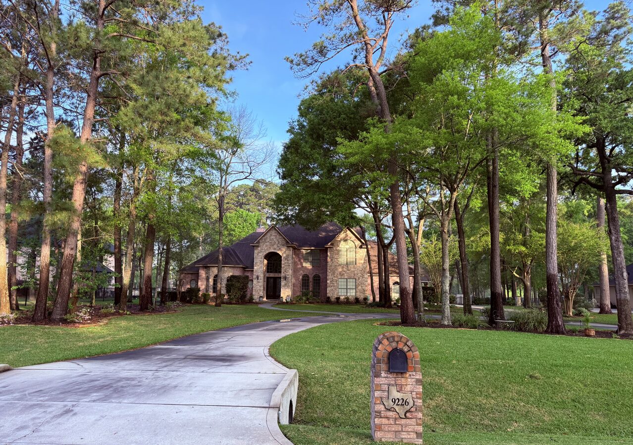 Wooded estate after trimming — full property view with manicured lawn